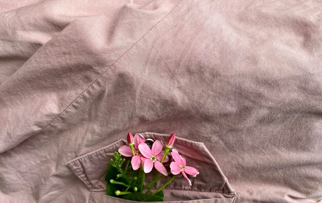 Un fiore rosa in una tasca di una camicia grigia