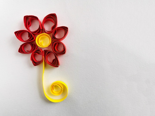 un fiore rosso e giallo su sfondo bianco Quilling un fiore di carta colorata