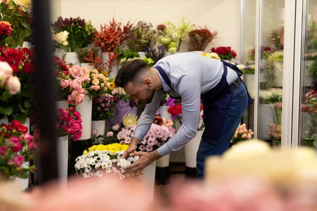 Un fiorista uomo sta preparando un negozio per la vendita di fiori per San Valentino ordina mazzi di fiori freschi