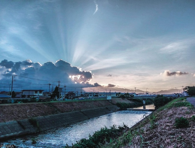 Un fiume attraversa una città con il sole che splende attraverso le nuvole