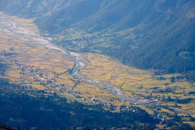 Un fiume attraversa una valle con un piccolo villaggio in lontananza.