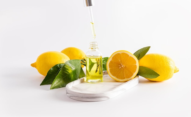 Un flacone cosmetico aperto riempito con una pipetta di siero antietà al limone per la cura della pelle del viso effetto lifting sfondo bianco