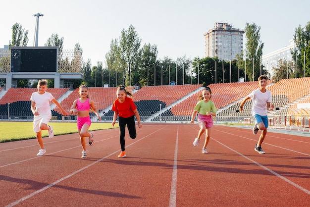 Un folto gruppo di bambini ragazzi e ragazze corrono e praticano sport allo stadio durante il tramonto Uno stile di vita sano