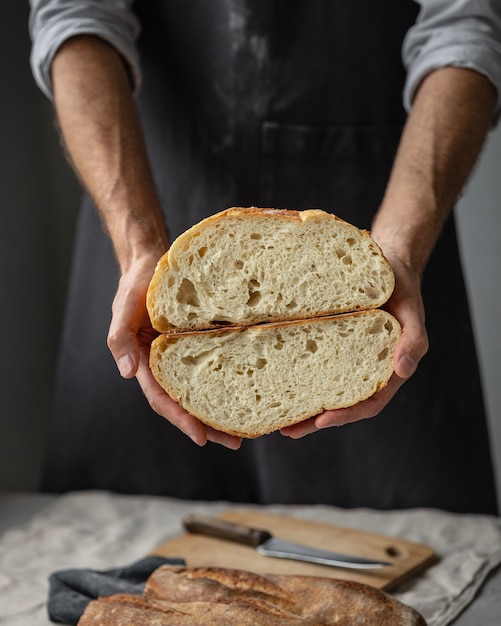 Un fornaio maschio europeo adulto tiene in mano un pane fresco rotondo un uomo in una panetteria tiene a