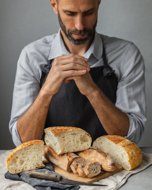 Un fornaio maschio europeo adulto tiene in mano un pane fresco rotondo un uomo in una panetteria tiene a