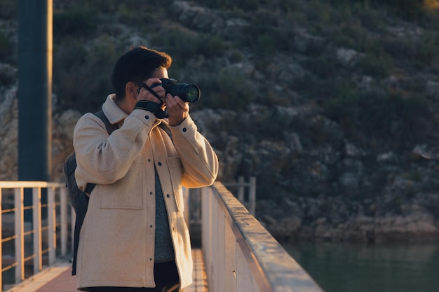 Un fotografo latino con una fotocamera scatta foto in una laguna al tramonto