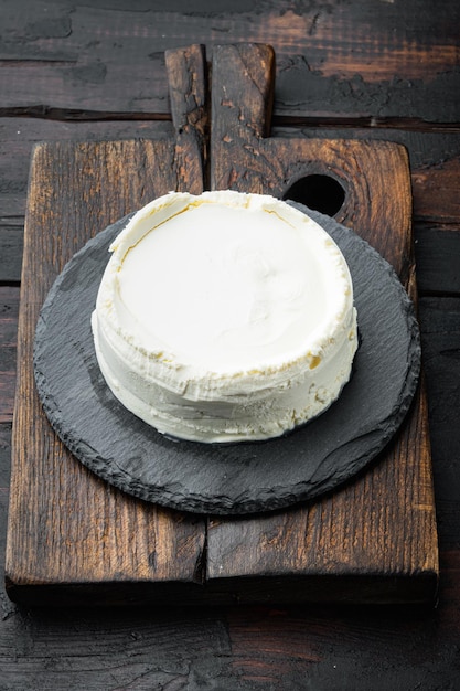 Un fresco, ricotta, sul tagliere di legno, sul vecchio fondo di legno scuro della tavola