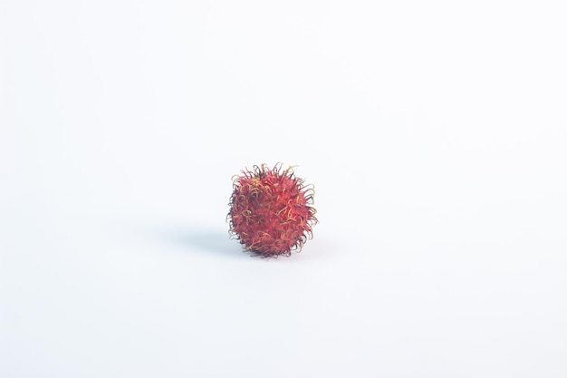 Un frutto rambutan rosso su sfondo bianco