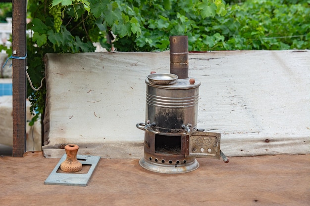 Un fumoso samovar turco con la porta della stufa aperta si trova nel cortile della casa