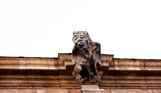 Un gargoyle in cima a un edificio con un cielo bianco alle spalle.