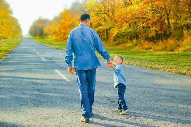Un genitore felice con il bambino sta camminando lungo la strada nel parco durante il viaggio nella natura