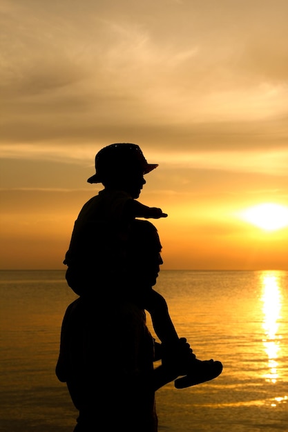 Un genitore felice con un bambino in riva al mare in natura su una silhouette di viaggio