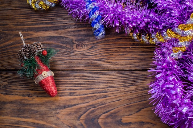 Un giocattolo dell'albero di natale e orpelli viola su fondo di legno marrone