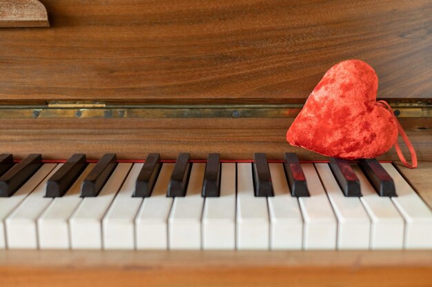 Un giocattolo imbottito rosso a forma di cuore si trova sul pianoforte Primo piano Fuoco selettivo