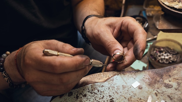 Un gioielliere esamina un anello d'oro prima di ripararlo in un'officina, primo piano