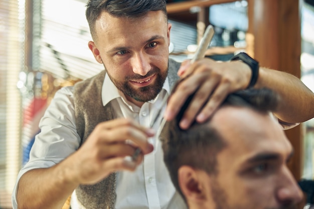 un gioioso barbiere che sorride e taglia i capelli della sua cliente