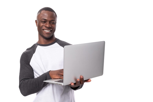 Un giovane africano con un taglio di capelli corto sta usando il laptop per il lavoro a distanza.