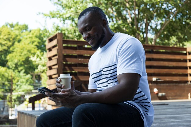 Un giovane afroamericano elegante con un kwa e uno smartphone in mano