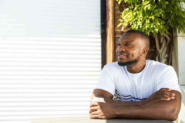 Un giovane afroamericano si siede a un tavolo fuori.
