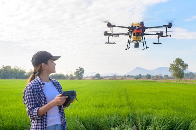 Un giovane agricoltore intelligente che controlla i droni che spruzzano fertilizzanti e pesticidi sui terreni agricoli