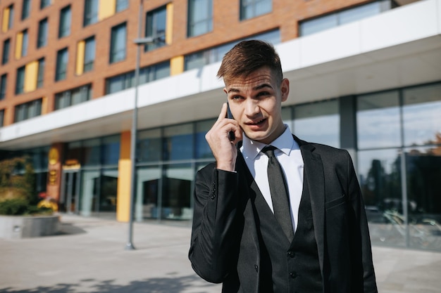 Un giovane americano caucasico vestito con un elegante completo da lavoro esprime la sua rabbia mentre è impegnato