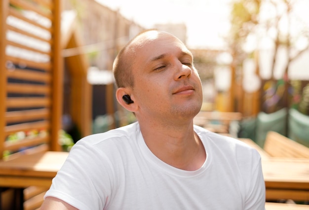 Un giovane ascolta la musica con gli auricolari, apprezza la melodia con gli occhi chiusi