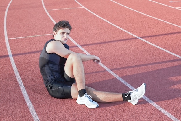 Un giovane atleta fa stretching. Sullo sfondo il tapis roulant.