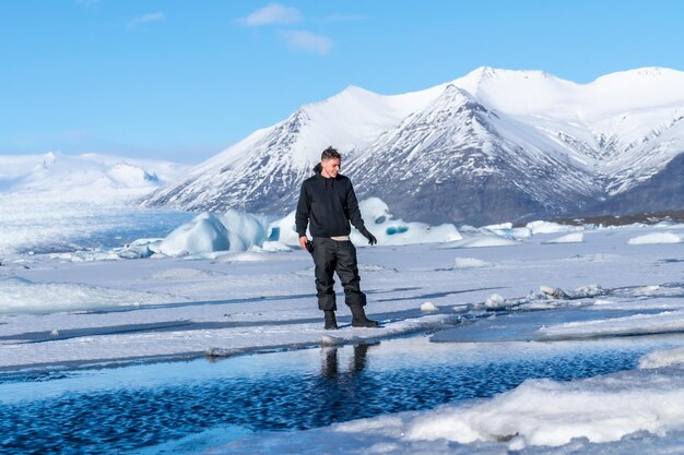 Un giovane avventuroso che cammina sul ghiacciato lago Jokulsarlon in inverno in Islanda
