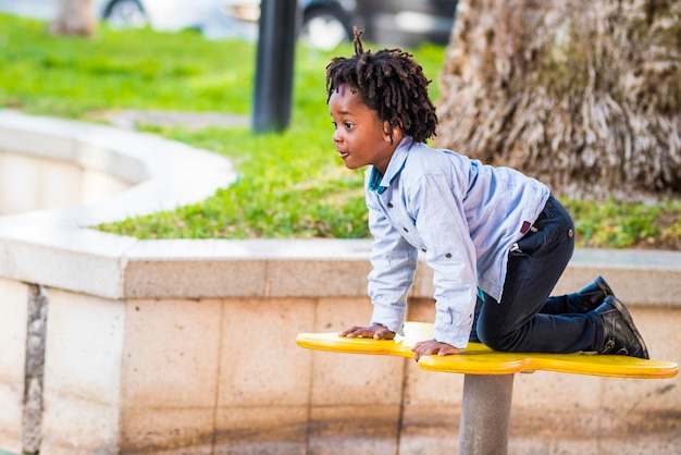 Un giovane bambino nero si diverte a divertirsi nel parco giochi nel parco cittadino Piccolo ragazzo che gioca da solo in attività ricreative all'aperto