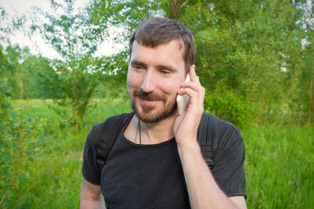 Un giovane barbuto che parla al cellulare nella foresta