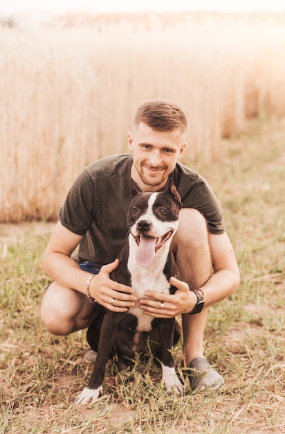 Un giovane cammina nella natura con un cane di razza Pit Bull Terrier