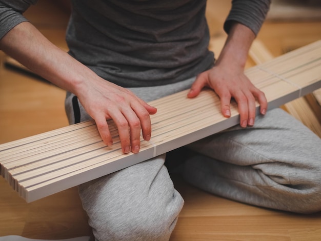 Un giovane caucasico conta le doghe di legno bianco per una base del letto