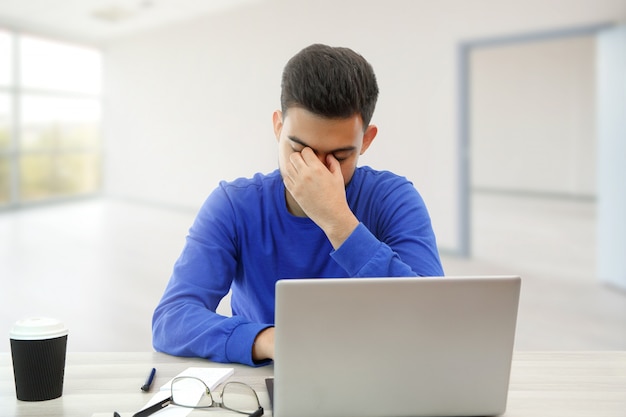 Un giovane che lavora su un computer portatile. è arrabbiato e stanco. su bianco isolato