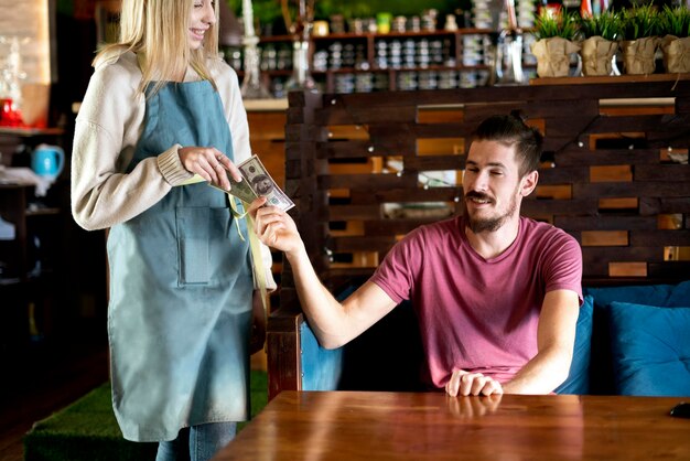 Un giovane che paga la cameriera per il suo ordine al ristorante