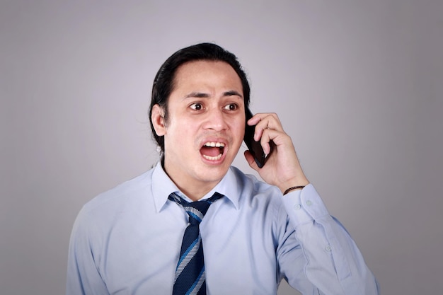 Un giovane che parla al telefono ha un'espressione scioccata e preoccupata
