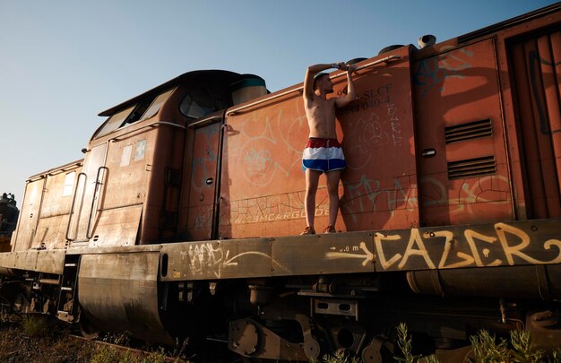 Un giovane che ripara un treno abbandonato con una chiave inglese dai toni arancioni del verde acqua