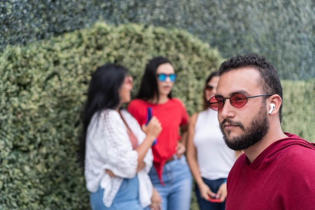 Un giovane con gli occhiali da sole che distoglie lo sguardo vicino agli amici