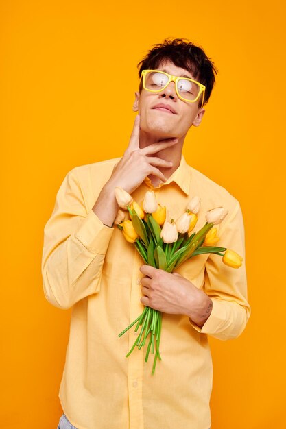 Un giovane con gli occhiali gialli con un mazzo di fiori in vacanza inalterato