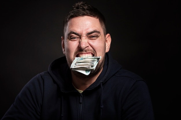 Un giovane con un pacco di soldi tra i denti. Avvicinamento.