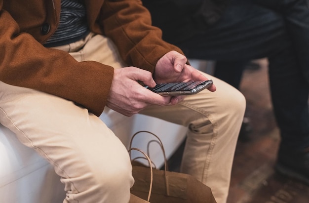 Un giovane con un telefono in mano è seduto su una panchina in un negozio