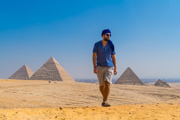 un giovane con un turbante blu che cammina vicino alle piramidi di Giza