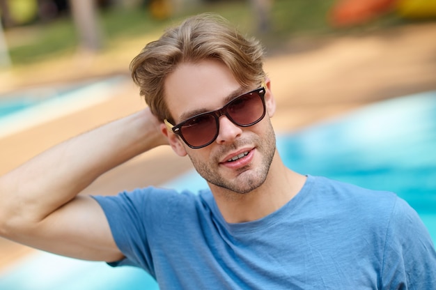 Un giovane con una maglietta blu e occhiali da sole che sembra sicuro di sé