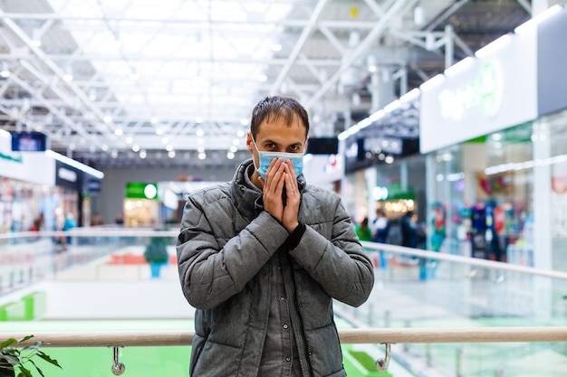 Un giovane con una maschera medica in un centro commerciale. L'uomo mascherato si protegge dall'epidemia del virus cinese "2019-nKoV"