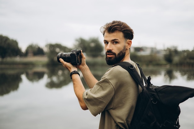 Un giovane con una moderna fotocamera SLR nelle sue mani su uno sfondo naturale