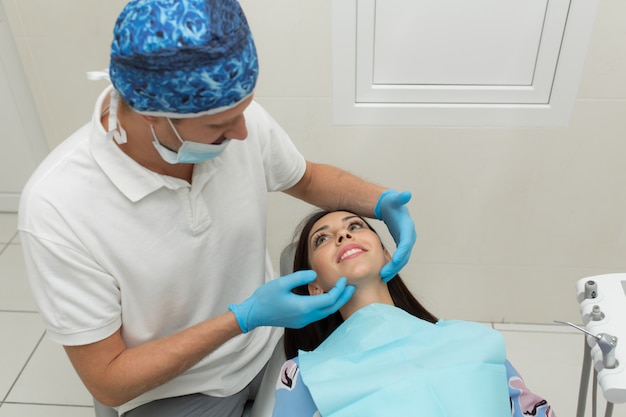 Un giovane dentista maschio e un paziente femminile felice. Scena di stile di vita dell'ufficio del dentista. Pratica medica. Assistenza sanitaria al paziente