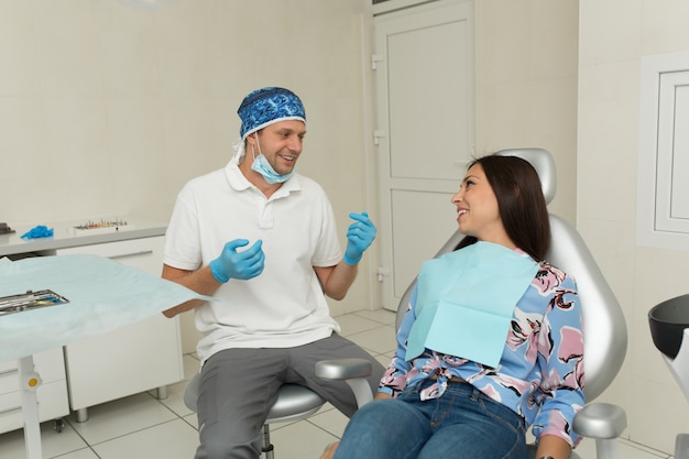 Un giovane dentista maschio e un paziente femminile felice. Scena di stile di vita dell'ufficio del dentista. Pratica medica. Assistenza sanitaria al paziente