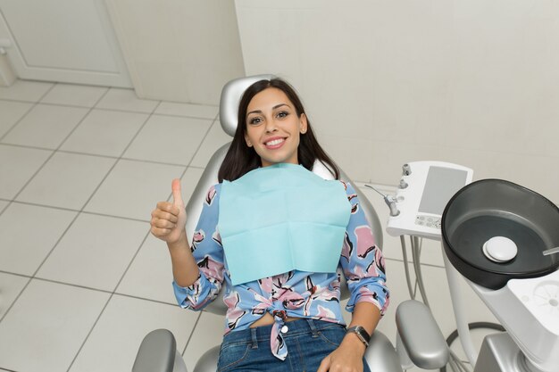 Un giovane dentista maschio e un paziente femminile felice. Scena di stile di vita dell'ufficio del dentista. Pratica medica. Assistenza sanitaria al paziente