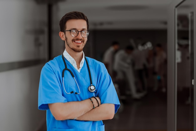 Un giovane dottore determinato con gli occhiali si trova con fiducia con le braccia incrociate nel corridoio di un