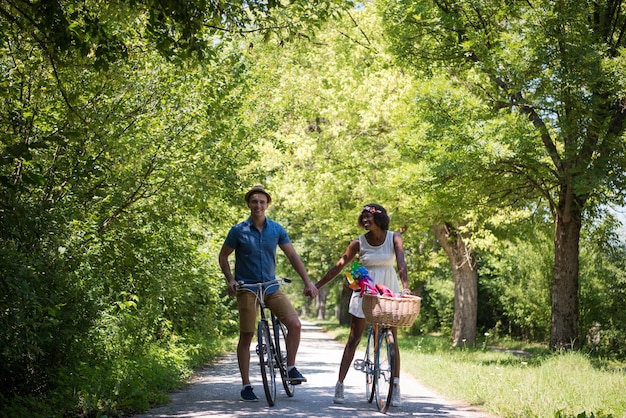 un giovane e una bella ragazza afroamericana che si godono un giro in bicicletta nella natura in una soleggiata giornata estiva