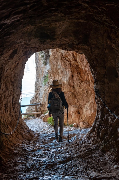 Un giovane escursionista nel tunnel del sentiero nel Parco Naturale del Penon de Ifach con la città di Calpe sullo sfondo Valencia Spagna Mar Mediterraneo Vista della spiaggia di La Fossa